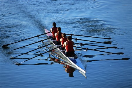 four rowers rowing a boat on open water